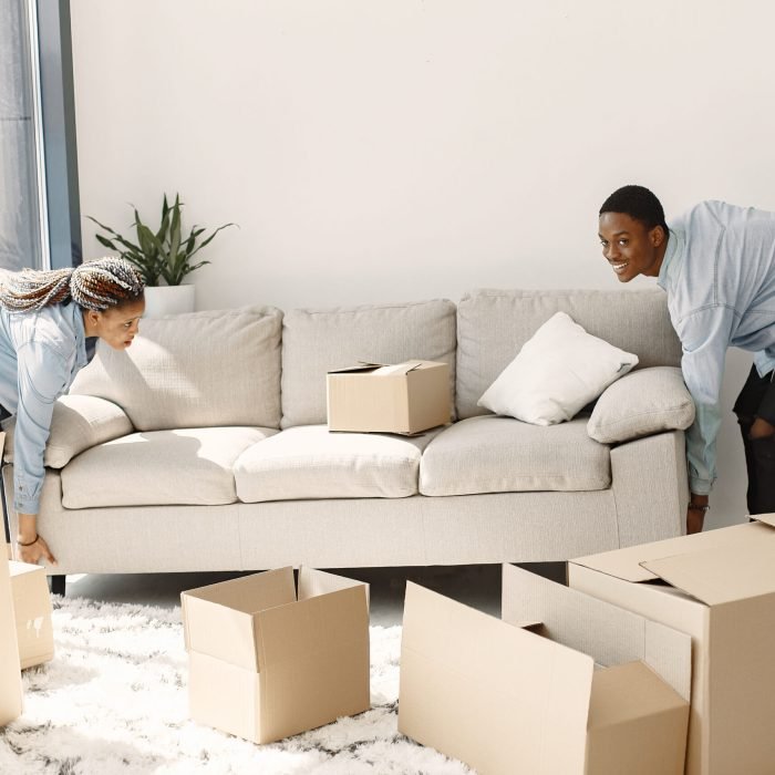 Couple with boxes moving into new home smiling Young couple moving in to new home together. African american couple with cardboard boxes.